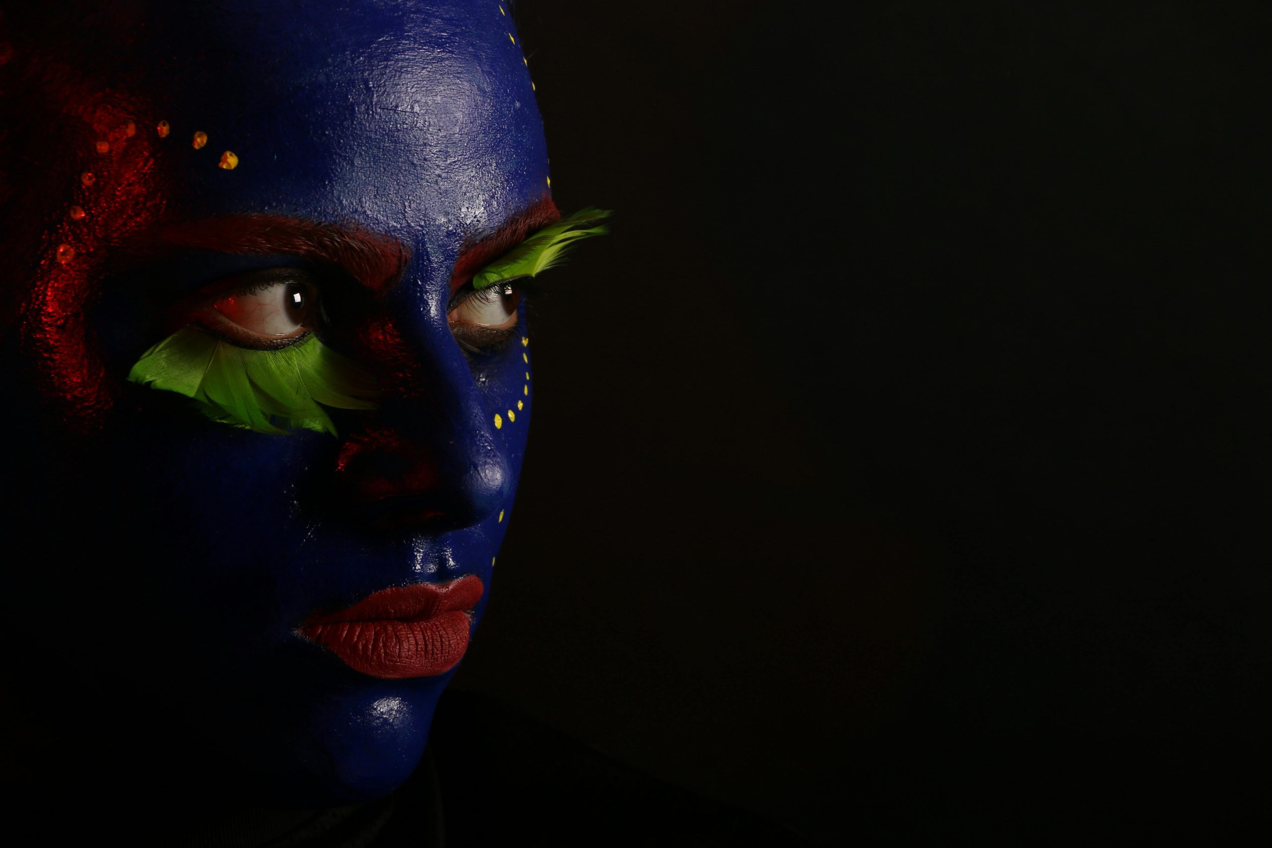 Striking portrait of a woman with colorful face paint, showcasing artistic and dramatic makeup.